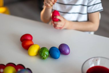 Güzel sarışın çocuk, oğlum, Paskalya için evde yumurta boyuyor ve boyuyor, bayrama hazırlanıyor.