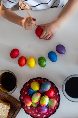 Güzel sarışın çocuk, oğlum, Paskalya için evde yumurta boyuyor ve boyuyor, bayrama hazırlanıyor.