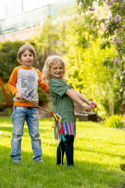 Happy children, siblings, enjoying Easter holiday together, tradition with handmade twig, braided whip made from pussy willow, traditional symbol of Czech Easter