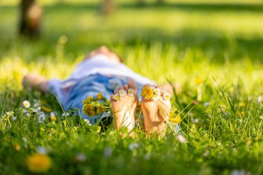 Parktaki çimenlerde oturan sevimli, şık, gülümseyen bir çocuğun portresi.