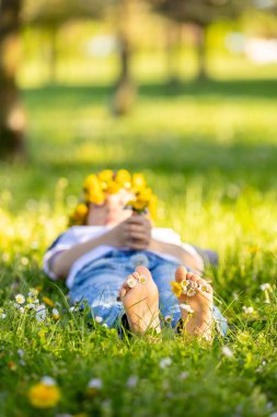 Parktaki çimenlerde oturan sevimli, şık, gülümseyen bir çocuğun portresi.