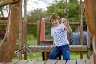 Çocuk, baharda oyun bahçesinde oynuyor, açık havada güzel havanın tadını çıkarıyor.