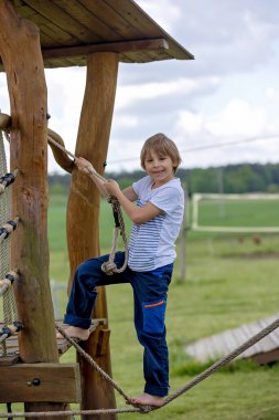 Çocuk, baharda oyun bahçesinde oynuyor, açık havada güzel havanın tadını çıkarıyor.