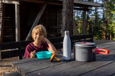 Mutlu çocuk, yol kenarındaki bir bankta yemek yiyor, Norveç 'te aile yemeği yiyor.