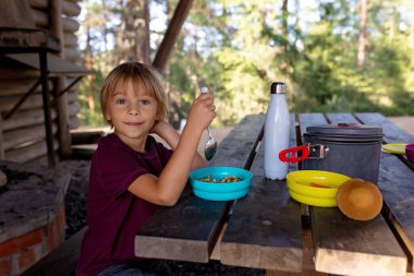 Mutlu çocuk, yol kenarındaki bir bankta yemek yiyor, Norveç 'te aile yemeği yiyor.