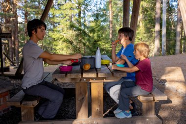 Mutlu çocuk, yol kenarındaki bir bankta yemek yiyor, Norveç 'te aile yemeği yiyor.