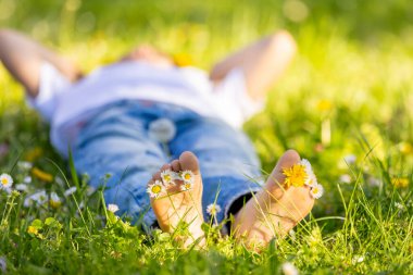 Parktaki çimenlerde oturan sevimli, şık, gülümseyen bir çocuğun portresi.