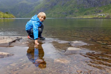 Kuzey Norveç, Lofoten 'in sonundaki küçük bir köyün manzarasının tadını çıkaran sevimli küçük bir çocuk.