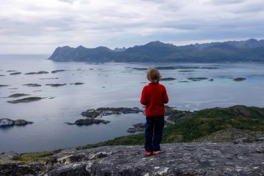 Çocuklu ve evcil hayvanlı aile, çocuklar ve yetişkinler Norveç 'in Senja adasında Sukkertoppen yolunda yürüyüş yapıyorlar.