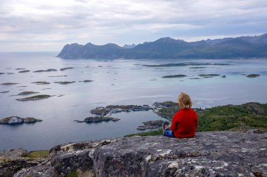 Çocuklu ve evcil hayvanlı aile, çocuklar ve yetişkinler Norveç 'in Senja adasında Sukkertoppen yolunda yürüyüş yapıyorlar.