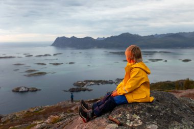 Çocuklu ve evcil hayvanlı aile, çocuklar ve yetişkinler Norveç 'in Senja adasında Sukkertoppen yolunda yürüyüş yapıyorlar.