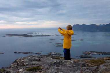 Çocuklu ve evcil hayvanlı aile, çocuklar ve yetişkinler Norveç 'in Senja adasında Sukkertoppen yolunda yürüyüş yapıyorlar.