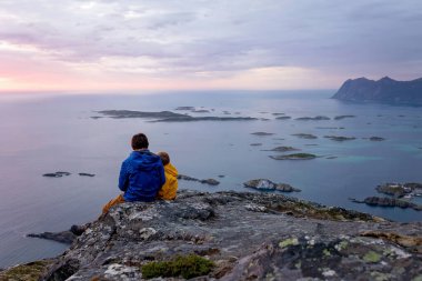 Çocuklu ve evcil hayvanlı aile, çocuklar ve yetişkinler Norveç 'in Senja adasında Sukkertoppen yolunda yürüyüş yapıyorlar.