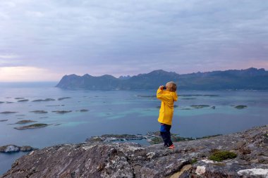 Çocuklu ve evcil hayvanlı aile, çocuklar ve yetişkinler Norveç 'in Senja adasında Sukkertoppen yolunda yürüyüş yapıyorlar.