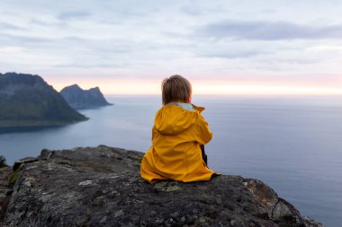 Çocuklu ve evcil hayvanlı aile, çocuklar ve yetişkinler Norveç 'in Senja adasında Sukkertoppen yolunda yürüyüş yapıyorlar.