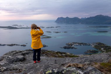 Çocuklu ve evcil hayvanlı aile, çocuklar ve yetişkinler Norveç 'in Senja adasında Sukkertoppen yolunda yürüyüş yapıyorlar.