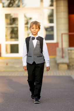 Sevimli birinci sınıf çocuğu, okula gidiyor. Birinci sınıf öğrencisi için okuldaki ilk gün, okula başlayan çocuk, öğretmene çiçek getiren, ilgilenen sırt çantası