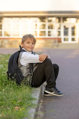 Sevimli birinci sınıf çocuğu, okula gidiyor. Birinci sınıf öğrencisi için okuldaki ilk gün, okula başlayan çocuk, öğretmene çiçek getiren, ilgilenen sırt çantası