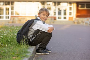Sevimli birinci sınıf çocuğu, okula gidiyor. Birinci sınıf öğrencisi için okuldaki ilk gün, okula başlayan çocuk, öğretmene çiçek getiren, ilgilenen sırt çantası