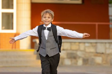 Sevimli birinci sınıf çocuğu, okula gidiyor. Birinci sınıf öğrencisi için okuldaki ilk gün, okula başlayan çocuk, öğretmene çiçek getiren, ilgilenen sırt çantası