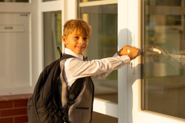Sevimli birinci sınıf çocuğu, okula gidiyor. Birinci sınıf öğrencisi için okuldaki ilk gün, okula başlayan çocuk, öğretmene çiçek getiren, ilgilenen sırt çantası