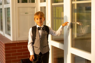 Sevimli birinci sınıf çocuğu, okula gidiyor. Birinci sınıf öğrencisi için okuldaki ilk gün, okula başlayan çocuk, öğretmene çiçek getiren, ilgilenen sırt çantası