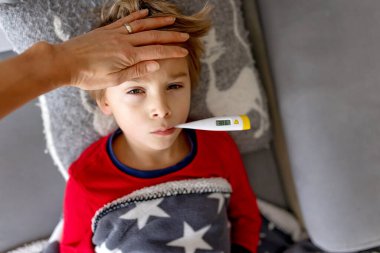 Hasta çocuk, anaokulu çocuğu, ateşi olan bir çocuk, evde köpeğiyle dinleniyor, annesi onu kontrol ediyor.