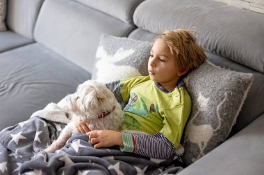 Hasta çocuk, anaokulu çocuğu, ateşi olan bir çocuk, evde köpeğiyle dinleniyor, annesi onu kontrol ediyor.