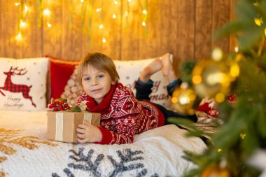 Tatlı sarışın çocuk, tatlı çocuk, Noel 'de Noel oyuncaklarıyla oynayan, Noel için güzel dekore edilmiş ev, ışıklarla dolu rahat bir yer.
