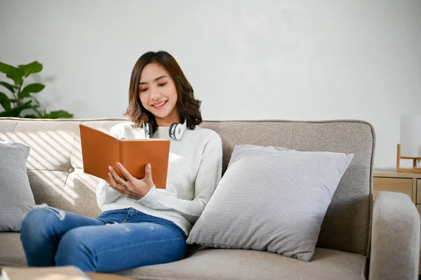 迷人的年轻亚洲女人喜欢在客厅的沙发上看书或小说 业余爱好和休闲概念 — 图库照片