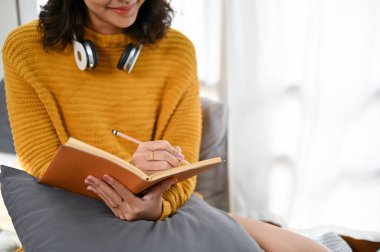 Rahat yatağında dinlenirken günlük ya da sabah günlüğünü bir deftere yazan güzel, genç Asyalı kadın. kırpılmış resim