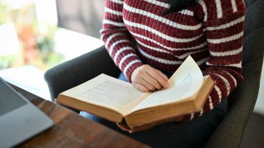 Kitap okuyan zeki, genç Asyalı bir üniversite öğrencisi kampüs kütüphanesinde otururken ders kitabı hakkında bilgi topluyor. kırpılmış resim