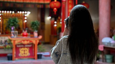 Güzel Asyalı kadın, Asya tapınağında tatildeyken kamerayla fotoğraf çekiyor. 