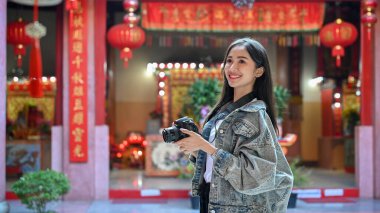 Genç ve güzel Asyalı bir kadının portresi elinde kamerayla tapınağa yaptığı ziyaret sırasında seyahat ediyor. 