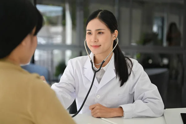 专业和有吸引力的亚洲女医生使用听诊器倾听病人的心脏和肺的声音 体格检查 — 图库照片