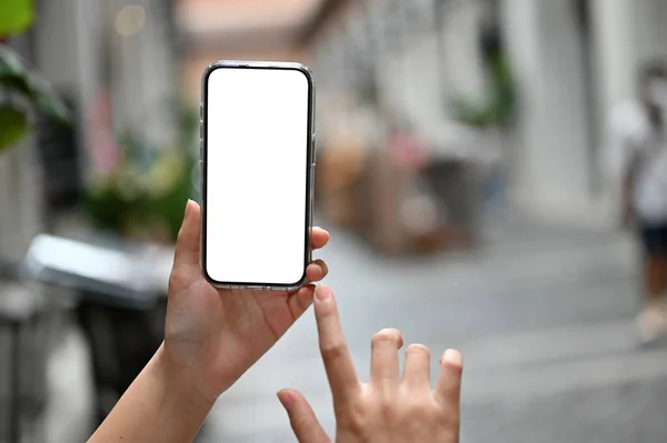 一个智能手机的白色屏幕模型被放在一个女人的手里 而她的手被城市广场模糊的背景所蒙蔽 — 图库照片
