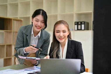 İki profesyonel ve güzel Asyalı iş kadını ya da finansal projeleri üzerinde birlikte çalışan kadın finans analistleri, bilgisayar ekranlarına bakıyorlar..