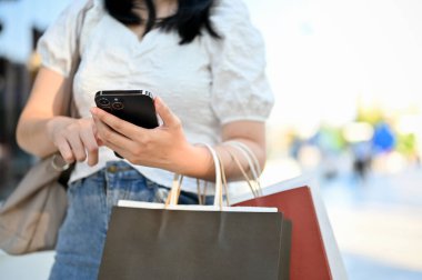 Kesilmiş atış, alışveriş merkezinin önünde duran akıllı telefonunu kullanan genç Asyalı kadın..