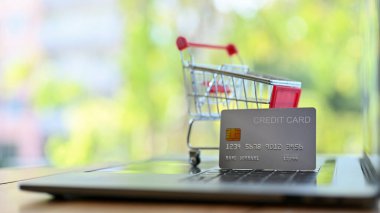 Klavyede gümüş bir kredi kartı ve alışveriş arabası var. Online alışveriş ve kredi kartı ödeme konsepti. yakın plan resim