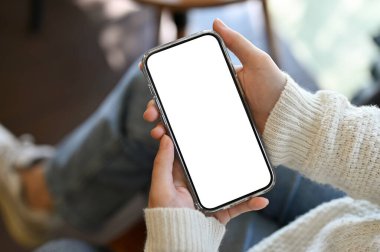 Kahve dükkanında rahatlarken akıllı telefonunu kullanan bir dişi. Akıllı telefon beyaz ekran modeli. yakın plan resim