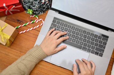 Tepeden çekimler, dizüstü bilgisayarda yazı yazan, projesini hazırlayan, iş yerinde Noel dekorlu dizüstü bilgisayar kullanan bir kadın..