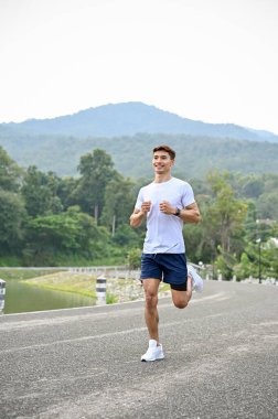 Aktif atletik genç Asyalı adam spor kıyafetleriyle dışarıda egzersiz yapıyor, sabah koşuyor ya da koşuyor..