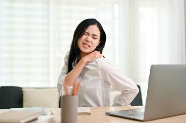 Uzun bir iş gününden sonra omuzları ve sırt ağrısı çeken genç ve güzel Asyalı iş kadını. aşırı çalışma, ofis sendromu konsepti