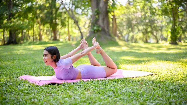 健康的年轻亚洲女子穿着运动服 在瑜伽垫上练习瑜伽 摆出高级瑜伽姿势 达努拉萨娜摆出姿势或鞠躬 — 图库照片
