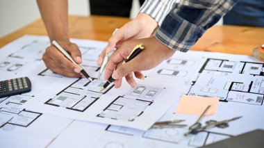 Yakın plan ve kırpılmış görüntü, takım ya da profesyonel inşaat mühendisleri ya da mimarlar planı tartışıyor ve birlikte inceliyorlar..