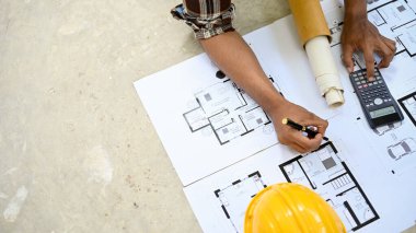 Üst görüş, profesyonel Asyalı erkek mühendis ya da mimar planı araştırıyor ve inceliyor. İnşaat, fabrika, mühendislik.