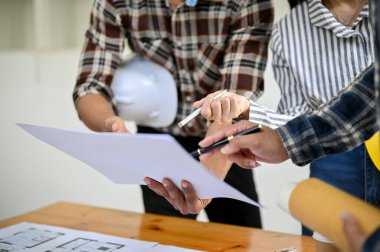 Profesyonel Asyalı mühendis ve mimar ekibi planı tartışıyor, ve ofiste birlikte çalışıyorlar. kırpılmış atış