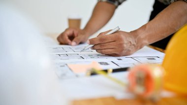 Yakın plan görüntü, profesyonel Asyalı erkek inşaat mühendisi ofiste planlar üzerinde çalışıyor..