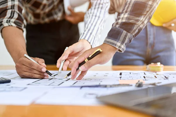 Stock image close-up hands image, Team of professional construction engineers or architects discussing, brainstorming and looking the blueprint together.