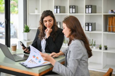 Başarılı ve profesyonel bin yıllık Kafkasyalı iş kadını asistanını dinlerken, mali rapora bakarak, ofiste birlikte çalışarak, yeni bir finans projesini anlatıyor..